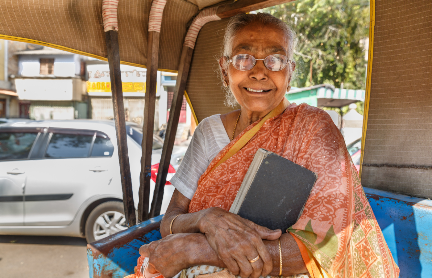 In einem Tuk-Tuk in Indien hält eine ältere Frau ihre Bibel fest an sich gedrückt.